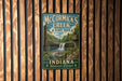 A vintage-style metal sign for McCormick's Creek State Park in Indiana, featuring a scenic image of a waterfall surrounded by lush greenery.
