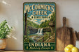 A vintage-style sign for McCormick's Creek State Park in Indiana, featuring a scenic image of a waterfall surrounded by lush greenery.