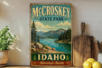 A vintage-style metal sign for McCroskey State Park in Idaho, featuring a scenic landscape with mountains, pine trees, and a lake.