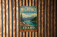 A vintage metal sign for McCroskey State Park in Idaho, featuring a scenic landscape with mountains, trees, and a lake.