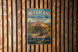 A vintage-style metal sign for McFarland State Historic Park in Arizona, featuring a desert landscape with a house and a horse-drawn carriage.