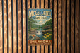 A vintage metal sign for McChee Creek State Park in Oklahoma, featuring a scenic landscape with a waterfall and flowers.