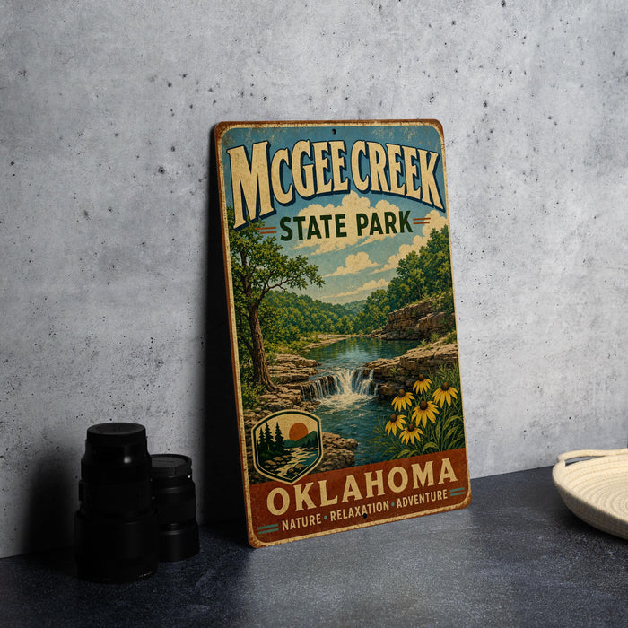 A vintage-style metal sign for McChee Creek State Park in Oklahoma, featuring a scenic landscape with a waterfall and flowers.
