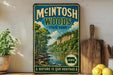 A vintage-style sign for Mcintosh Woods State Park in Iowa, featuring a scenic landscape with a river and forest.