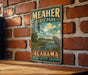 A vintage-style metal sign for Meacher State Park in Alabama, featuring a scenic illustration of a bird and a wooden dock.