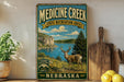 a vintage-style sign for Medicine Creek State Recreation Area in Nebraska, with a scenic landscape of mountains, a lake, and a deer in the foreground.