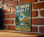 A vintage-style metal sign for the Metamora-Hadley Recreation Area in Michigan, featuring a scenic landscape with a river and mountains.