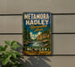 A vintage metal sign for Metamora-Hadley Recreation Area in Michigan, featuring a scenic landscape with a waterfall and pine trees.