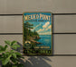 A vintage-style metal sign for Mexico Point State Park, featuring a scenic landscape with a lake and mountains, mounted on a wall.