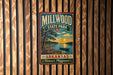 A vintage-style metal sign for Millwood State Park in Arkansas, featuring a scenic landscape with a lake, trees, and a sunset.
