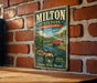 A vintage-style metal sign for Milton State Park in Pennsylvania, featuring a scenic illustration of a river and a red bridge.