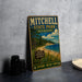 A vintage metal sign for Mitchell State Park, Michigan, featuring a scenic landscape with a beach, pine trees, and a lake.