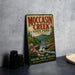 A vintage-style metal sign for Moccasin Creek State Park in Georgia, featuring a scenic illustration of the creek and mountains.