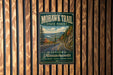 A vintage-style metal sign for the Mohawk Trail in Massachusetts, featuring a scenic mountain landscape and a winding road.