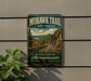 A vintage-style metal sign for the Mohawk Trail in Massachusetts, featuring a scenic mountain landscape with a winding road.