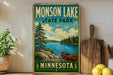 A vintage-style metal sign for "Monson Lake State Park" in Minnesota, featuring a scenic landscape with a lake, pine trees, and a canoe.