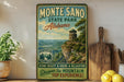 A vintage-style metal sign for Monte Sano State Park in Alabama, featuring a scenic image of a mountain with a lookout tower.