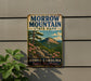 A vintage metal sign for Morrow Mountain State Park in North Carolina, featuring a scenic landscape with mountains, trees, and flowers.