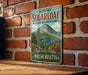 A vintage metal sign for Mount Sugarloaf State Reserve in Massachusetts, featuring a scenic mountain landscape with a lake and pine trees.