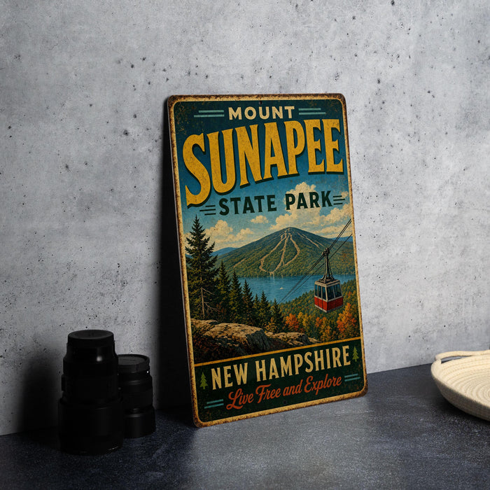 A vintage metal sign for Mount Sunapee State Park in New Hampshire, featuring a scenic mountain landscape with a cable car and the text "New Hampshire Live Free and Explore".