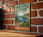A vintage-style sign for Mouselail Landing State Park in Tennessee, featuring a scenic landscape with a lake, mountains, and a bridge.