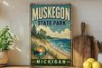 A vintage-style sign for Muskegon State Park in Michigan, featuring a scenic beach landscape with pine trees, a lake, and a sunset.
