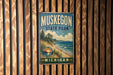 A vintage metal sign for Muskegon State Park, featuring a scenic landscape with a beach, mountains, and a lake.