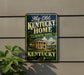 A vintage-style sign for Kentucky State Park, featuring a house and a steamboat, mounted on a wall next to a plant.