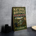 A vintage-style metal sign for the Natural Bridge Battlefield Historic State Park in Florida, featuring an illustration of the bridge and surrounding landscape.