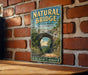 A vintage-style metal sign for Natural Bridge State Park in Massachusetts, featuring a scenic image of the bridge surrounded by lush greenery.
