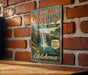 A vintage-style sign for Natural Falls State Park in Oklahoma, featuring a waterfall and lush greenery, is displayed on a brick wall.