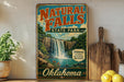 A vintage-style sign for Natural Falls State Park in Oklahoma, featuring a waterfall and lush greenery.