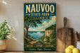 a vintage-style sign for Nauvoo State Park in Illinois, with a scenic landscape of a lake and mountains in the background.