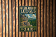 A vintage-style metal sign for Nelson-Kennedy Lidges State Park in Ohio, featuring a scenic landscape with a cliff and trees.