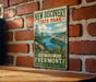 A vintage-style metal sign for New Discovery State Park in Vermont, featuring a scenic landscape with a lake and mountains.