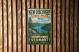A vintage-style metal sign for New Discovery State Park, featuring a scenic landscape with mountains, a lake, and pine trees.