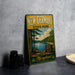 A vintage-style metal sign for New Germany State Park, featuring a scenic landscape with a lake and trees, is displayed on a gray countertop.
