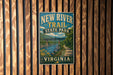 A vintage-style metal sign for the New River Trail State Park in Virginia, featuring a scenic illustration of a river and mountains.