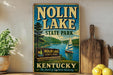 A vintage-style sign for Nolin Lake State Park in Kentucky, featuring a sailboat on the lake and a scenic landscape.