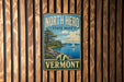 A vintage metal sign for North Hero State Park in Vermont, featuring a scenic landscape with a sailboat on the water.