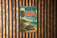A vintage metal sign for North Peninsula State Park in Florida, featuring a beach scene with a turtle and palm trees.