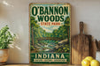 A vintage-style sign for O'Bannon Woods State Park in Indiana, featuring a scenic illustration of a forest and a bridge.