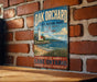 A vintage-style sign for Oak Orchard State Marine Park in New York, featuring a lighthouse and a beach scene.