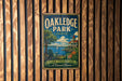 A vintage metal sign for Oakledge Park in Vermont, featuring a scenic illustration of the park with a lake, a building, and a boat.