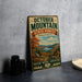 A vintage metal sign for October Mountain State Forest in Massachusetts, featuring a scenic landscape with autumn foliage and a lake.