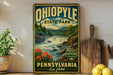 A vintage-style poster of Ohio State Park, featuring a scenic landscape with a waterfall and mountains, is displayed on a wall next to a wooden cutting board and some potted plants.