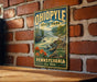 A vintage-style metal sign for Ohio Park, Pennsylvania, featuring a scenic image of a waterfall and mountains.