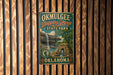 A vintage-style metal sign for Okmulgee-Drip Springs State Park in Oklahoma, featuring a waterfall and a stone structure.