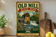 a vintage-style sign for Old Mill State Park in Minnesota, with a scenic illustration of a waterfall and a wooden building. The sign is displayed on a shelf next to a potted plant and a wooden cutting board, along with some lemons.