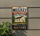 A vintage-style metal sign for the Old Mulkey Meetinghouse, a historic site in Kentucky, featuring a white building with a red roof and surrounded by trees.